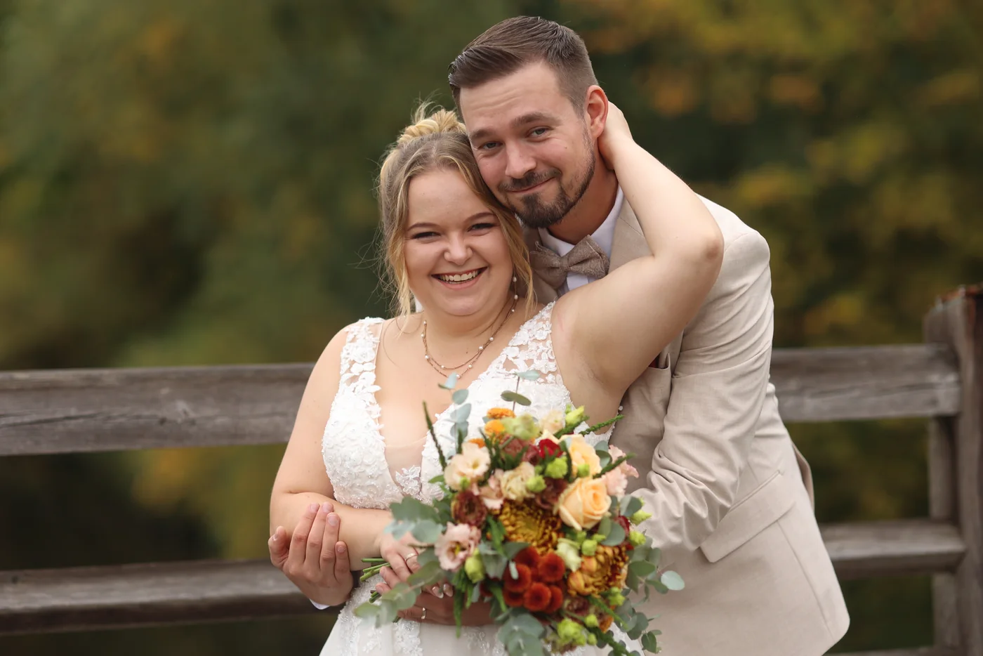 Jennifer und Tobias lachen gemeinsam vor herbstlichen Bäumen