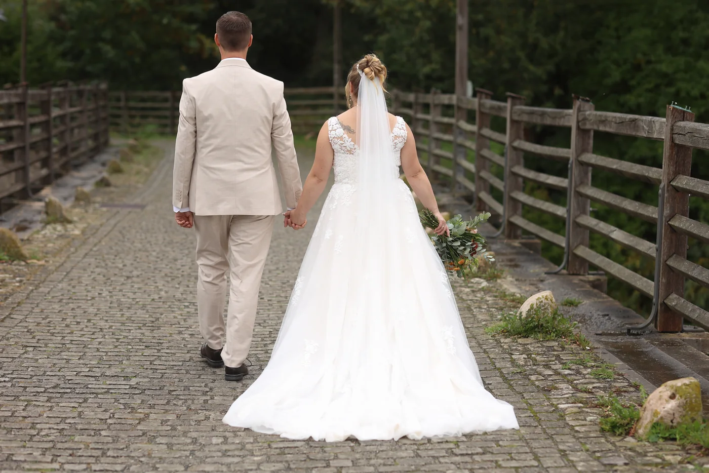 Jennifer und Tobias gehen Hand in Hand über den gepflasterten Weg