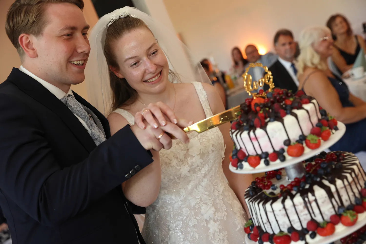 Brautpaar schneidet lachend die Hochzeitstorte an